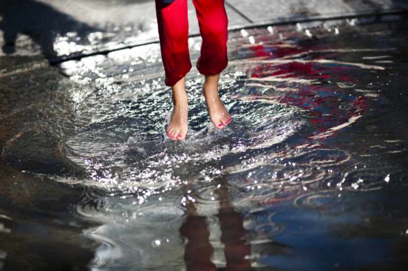 Madeline Glass, 6, splashes around in a wading pool in the children's area of Klyde Warren...