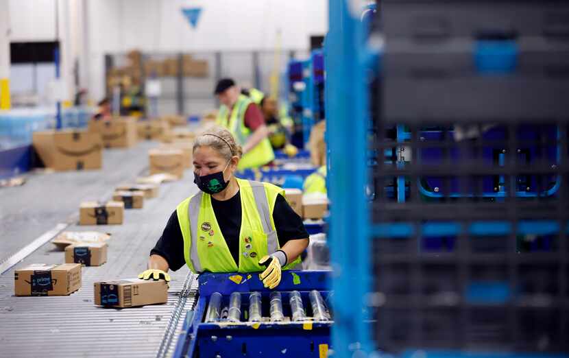 Amazon workers sort early Prime Day packages as they arrive at one of the company's largest...