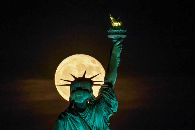 The Strawberry Supermoon rises in front of the Statue of Liberty in New York, June 14, 2022....
