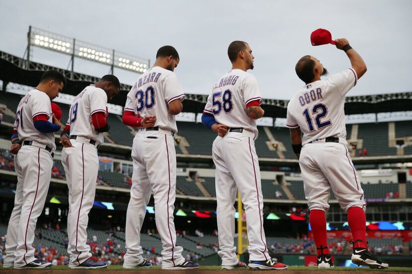 Texas Rangers second baseman Rougned Odor (12) stands with teammates while pointing his hat...