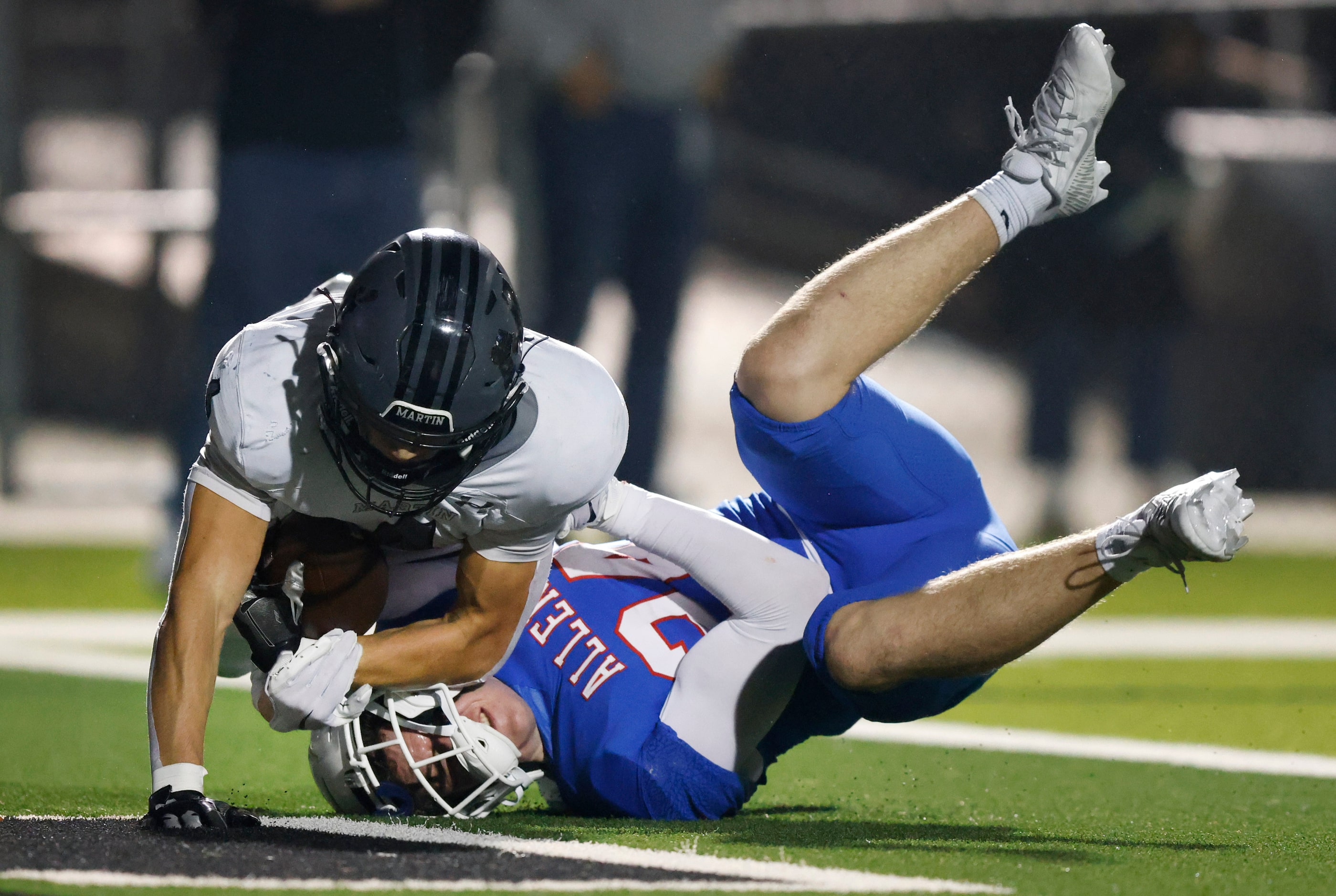 Arlington Martin wide receiver Logan Baresh (4) lands on Allen linebacker Mitchell Neu (24)...