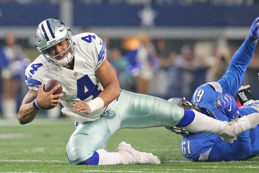 Dallas Cowboys quarterback Dak Prescott (4) is tripped up by Detroit Lions defensive end...