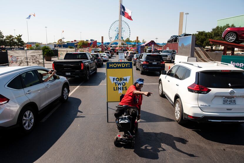 Staffer Betty Williams, 62, waves to vehicles to form two lines before receiving their...