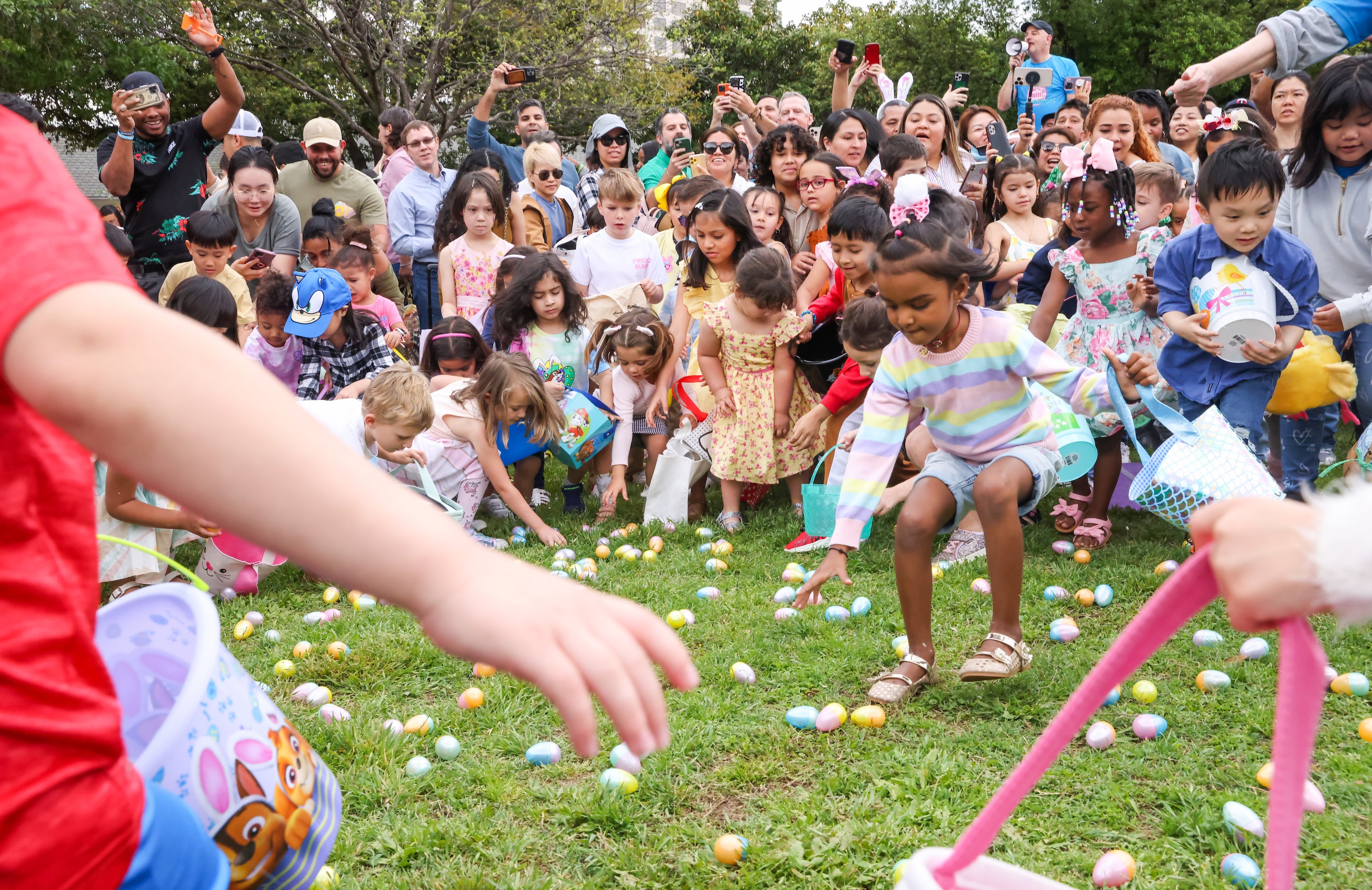 Kids rush to gather candy-filled eggs after a countdown to the start of an egg hunt at the...