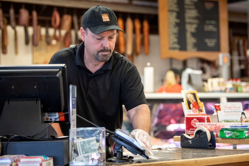 Karl Kuby Jr., owner of Kuby's Sausage House and European Market, sanitizes the credit card...