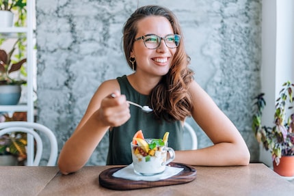 Young cheerful woman eating fruit salad.