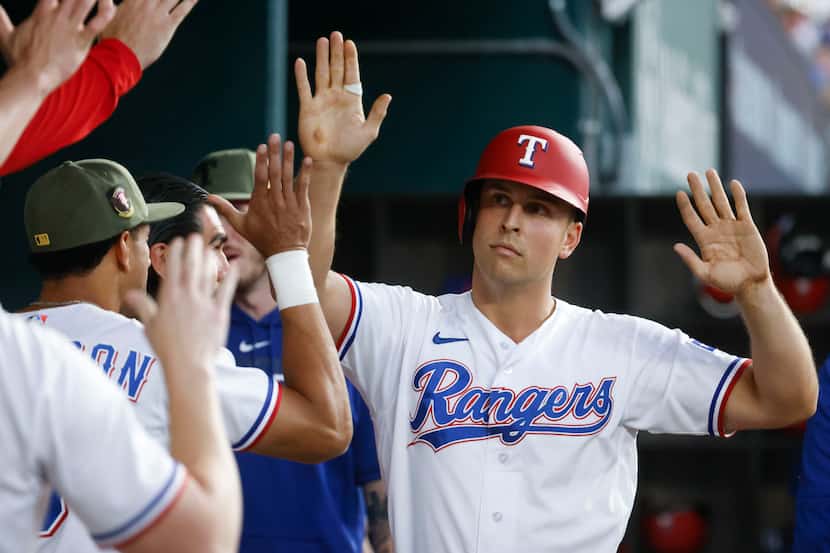 Texas Rangers Nathaniel Lowe cheers with his teammates after scoring on a passed ball during...