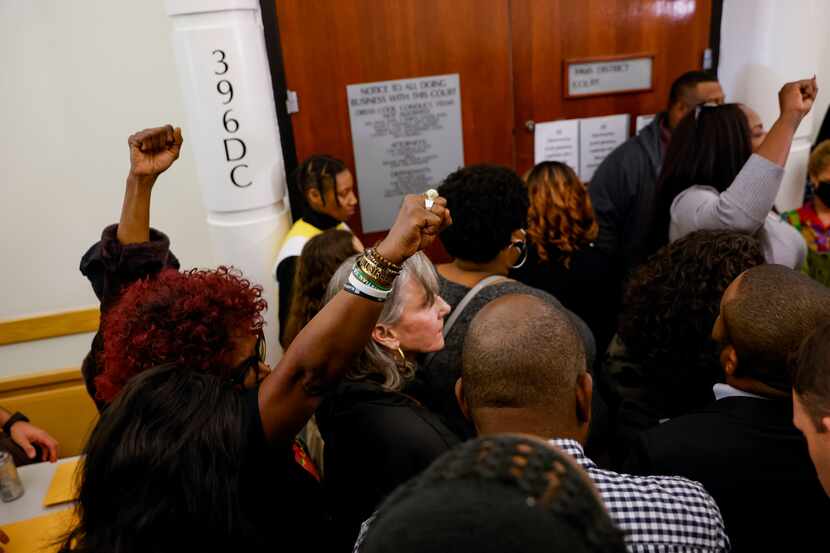 People raise their fists outside of 369th District Court before the verdict is announced in...