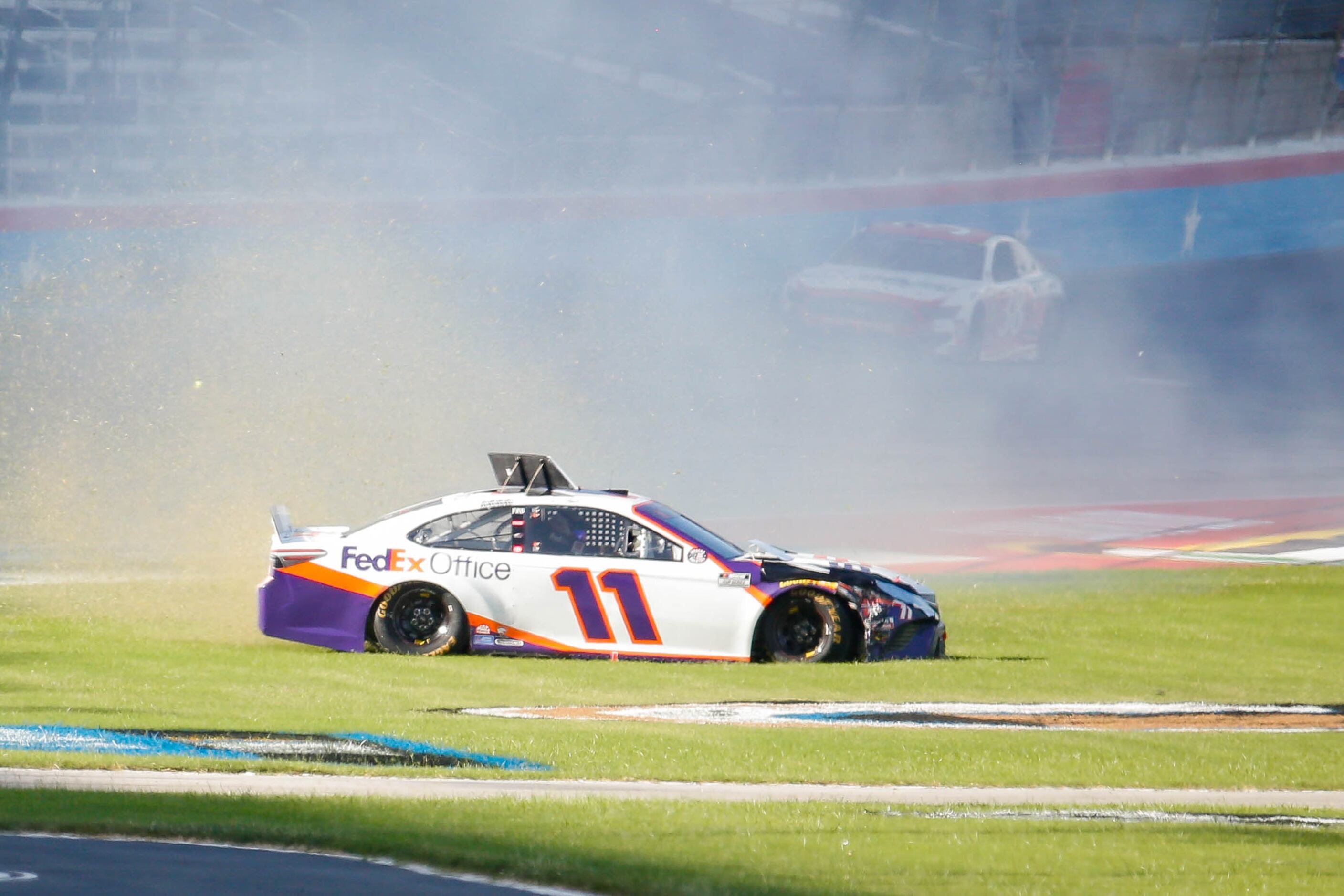 Denny Hamlin (No. 11) slides onto the grass after crashing during the NASCAR Cup Series...