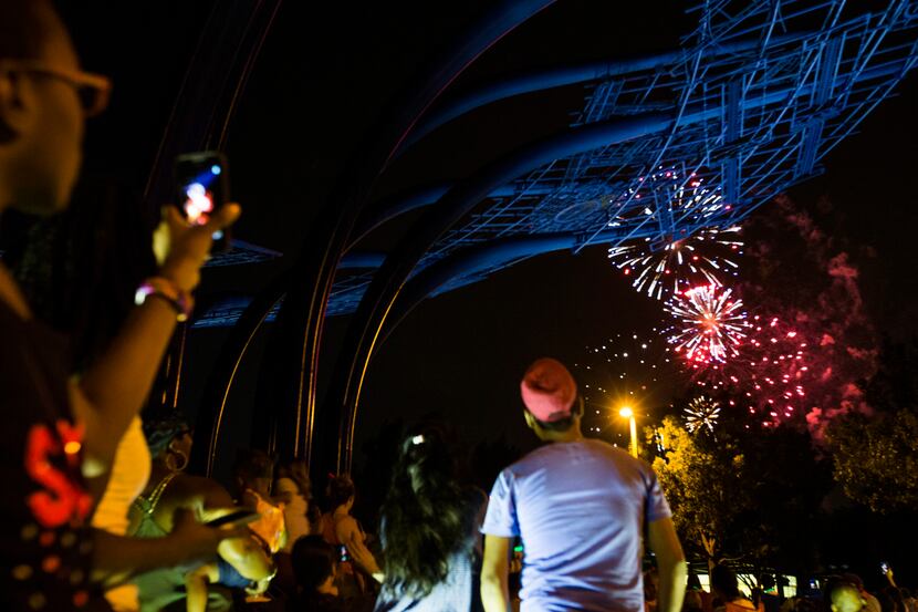 Spectators watch fireworks from the Blueprints sculpture during the Addison Kaboom Town!...