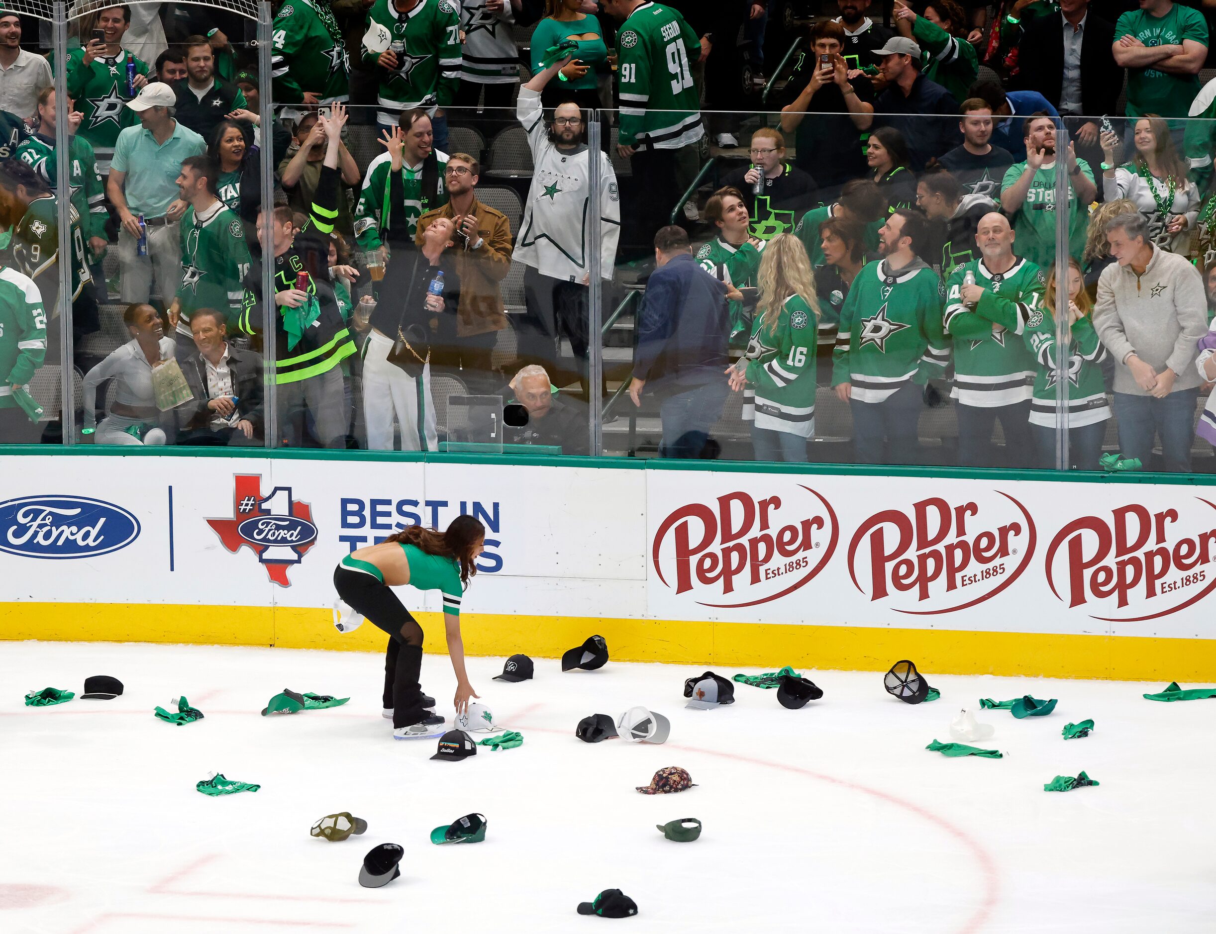 A Dallas Stars Ice Girl collects hats thrown on the ice following Dallas Stars center Joe...