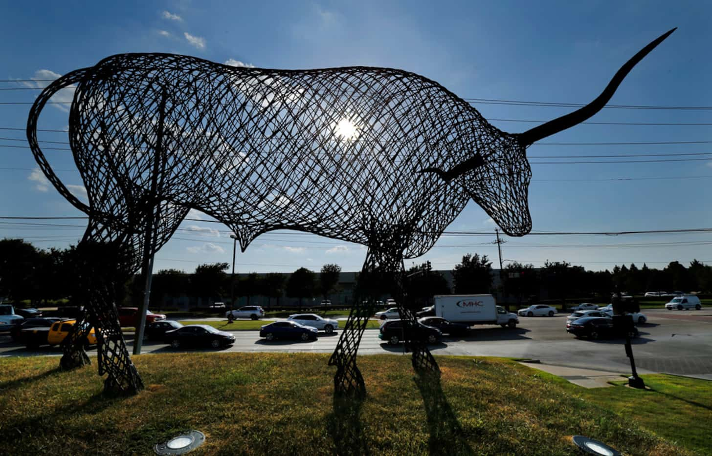 A large longhorn made out of steel looms over evening rush hour along Belt Line Road at...