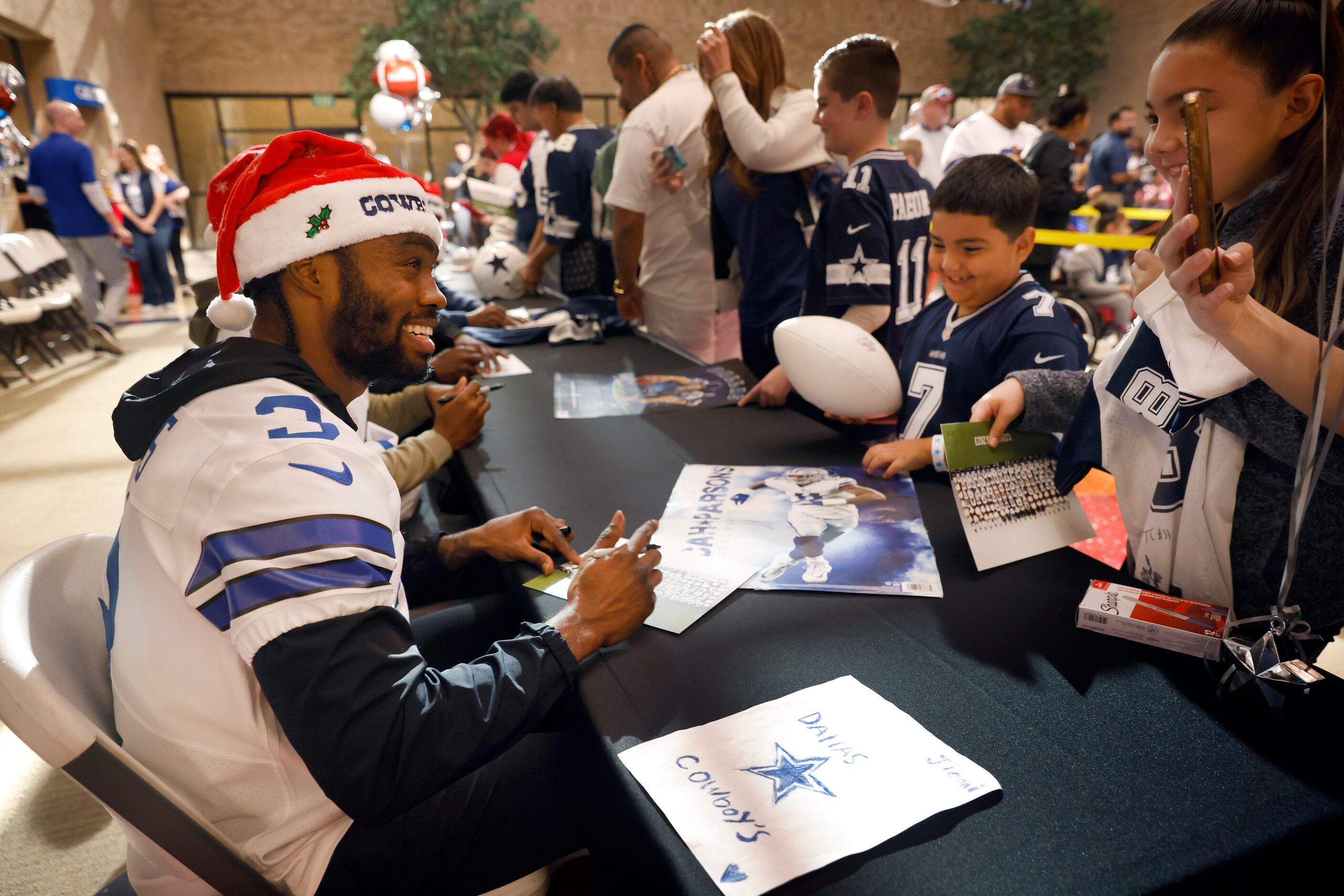 Dallas Cowboys wide receiver Brandin Cooks (left) signs autographs for in-patient kids and...