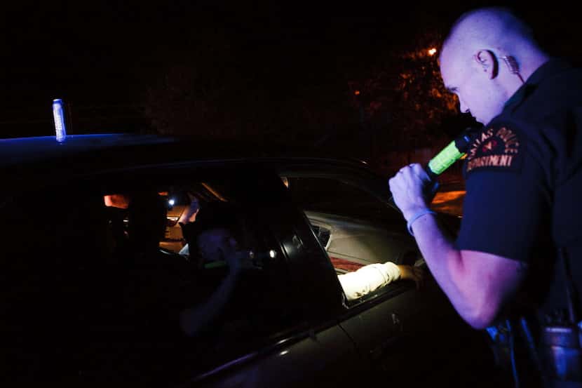 Dallas police Officer Bryan Burgess shines his flashlight into a car before arresting the...