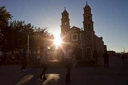 Pedestrians walk past a cathedral in the central square of Ciudad Juarez, Mexico. (File...