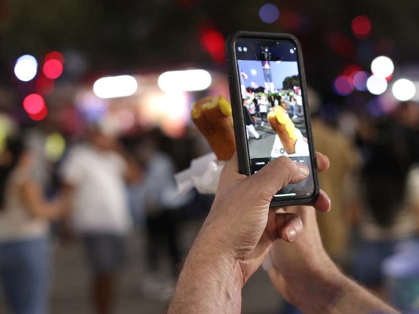 A fairgoer takes a picture of his Fletcher's corny dog before finishing it off Monday.