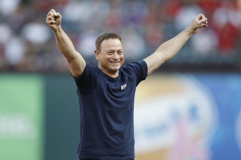 Gary Sinise cheers after he throws the honorary first pitch at Rangers Ballpark in Arlington...