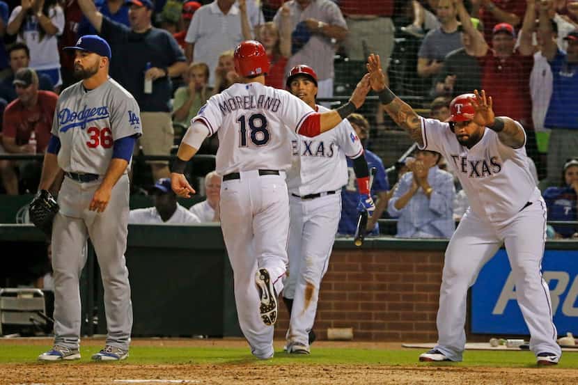 Texas first baseman Mitch Moreland is greeted by Prince Fielder, right, and Leonys Martin as...