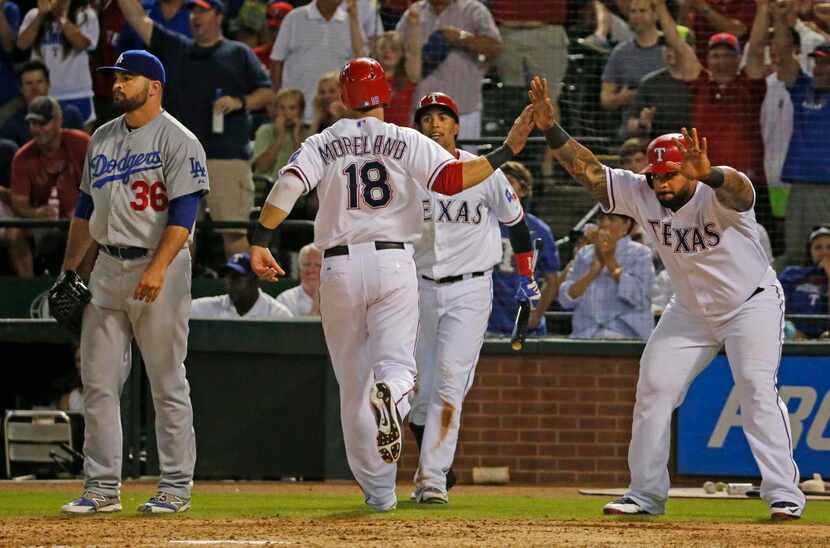 Texas first baseman Mitch Moreland is greeted by Prince Fielder, right, and Leonys Martin as...