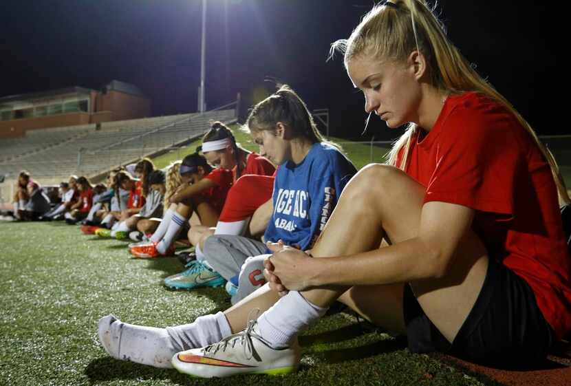 
Coppell High School junior Shay Johnson (right) prays with her teammates before an early...