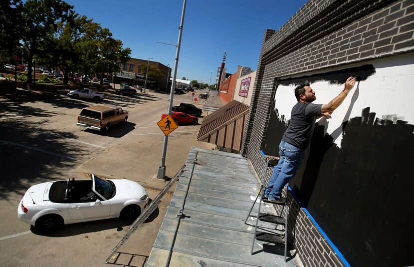 
Painter and tattoo artist Lucas Cervellini paints the marquee on the new Intrinsic...