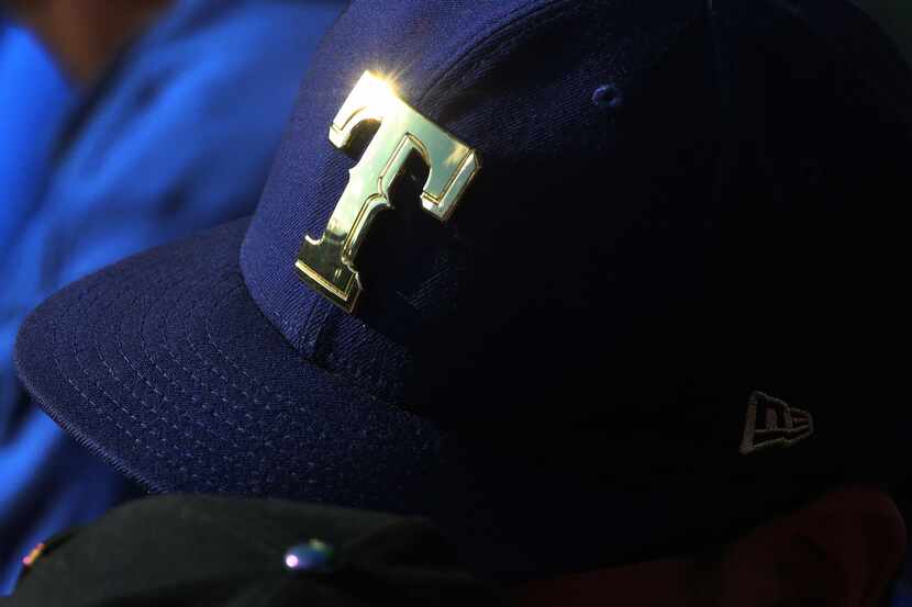 The sun glints off a metalic Rangers logo on the hat of a fan during the Houston Astros vs....