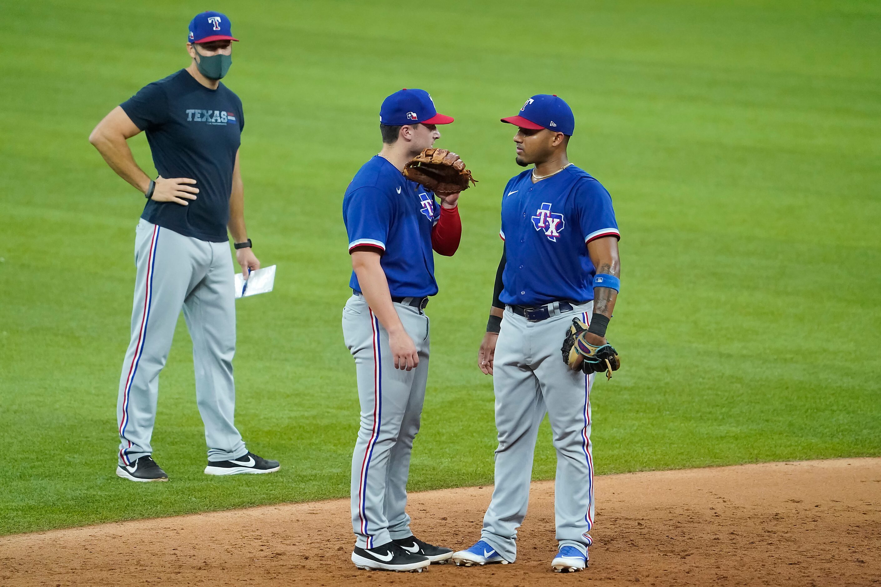 Texas Rangers infielder Justin Foscue (center) talks with infielder Andy Ibanez as field...