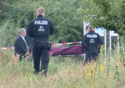 In this image taken from video police officer look on as the body of a 17-years-old attacker...