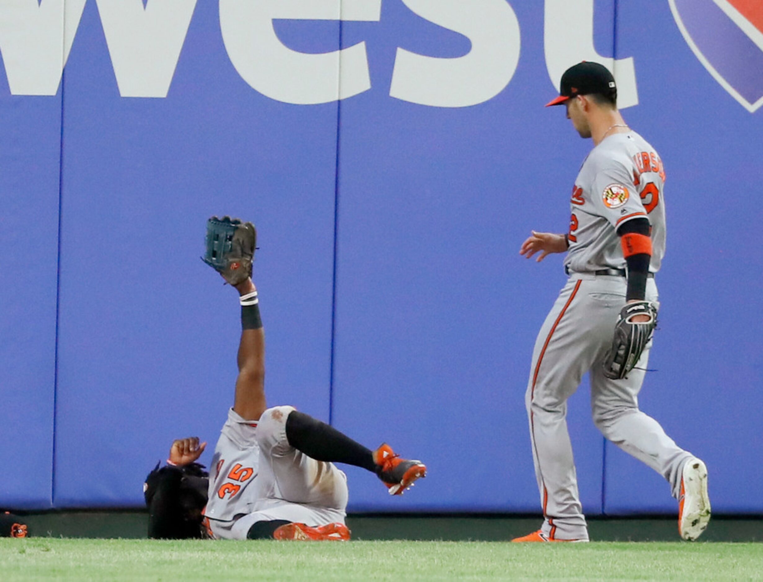 Baltimore Orioles left fielder Dwight Smith Jr. holds his glove up after hitting the wall...