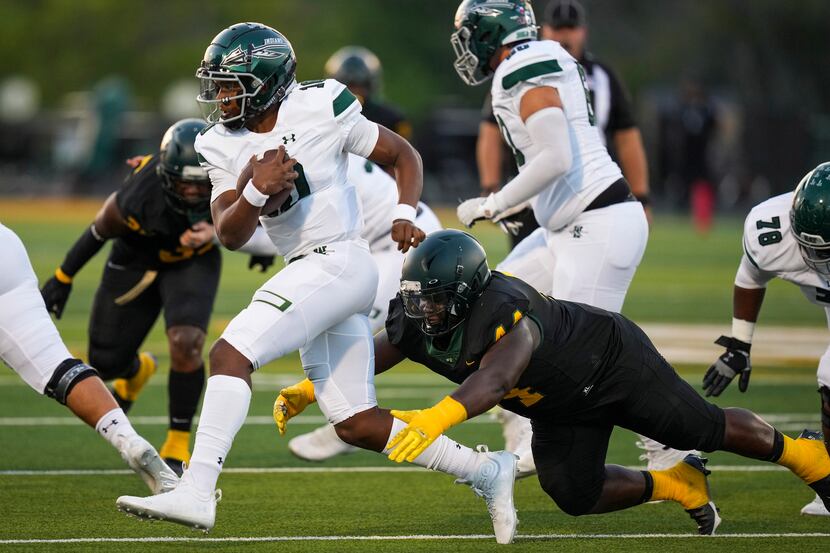 Waxahachie quarterback Roderick Hartsfield Jr. (10) is tripped up by DeSoto defensive...