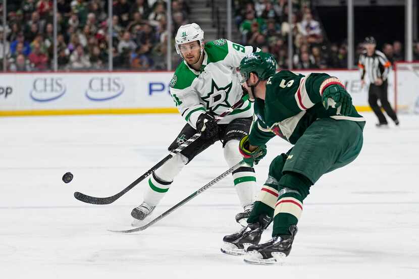Dallas Stars center Tyler Seguin (91), left, controls the puck while defended by Minnesota...