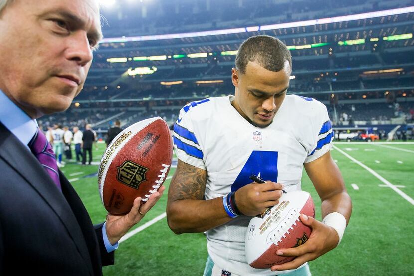 Dallas Cowboys quarterback Dak Prescott autographs a football after the Cowboys victory over...
