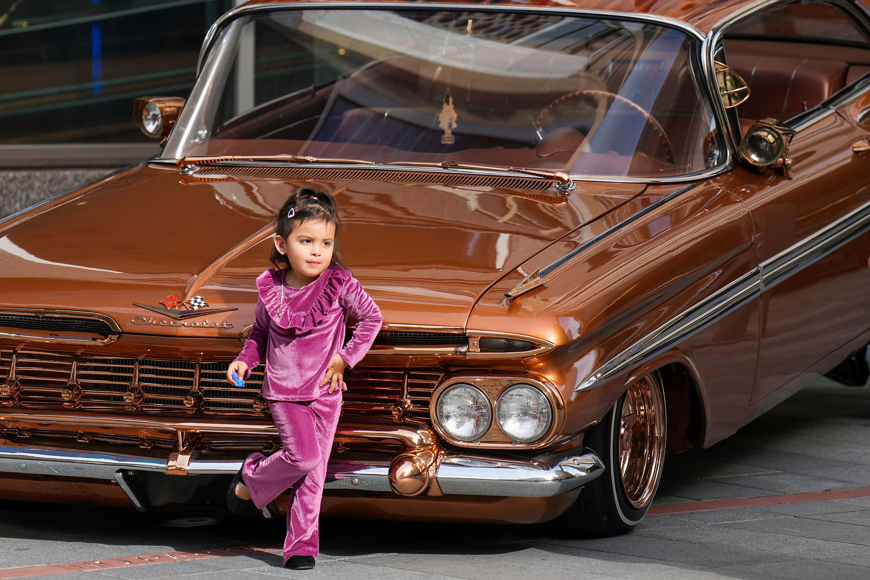 Kairi Sanchez, 2, strikes a pose next to a display of low riders during a celebration of the...