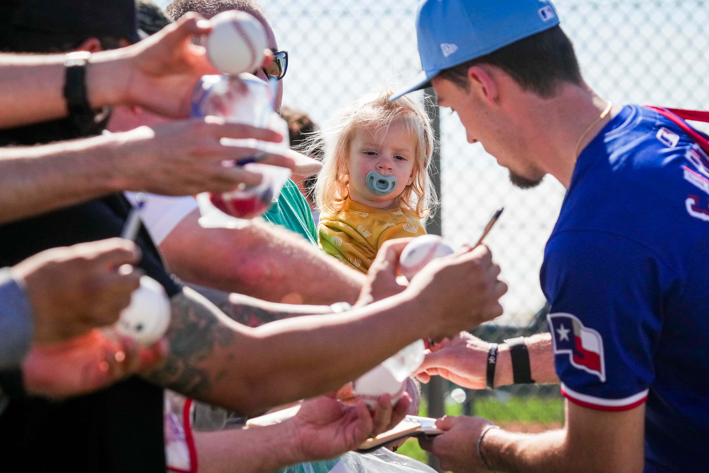 Texas Rangers outfielder Evan Carter signs autographs during the first full squad spring...