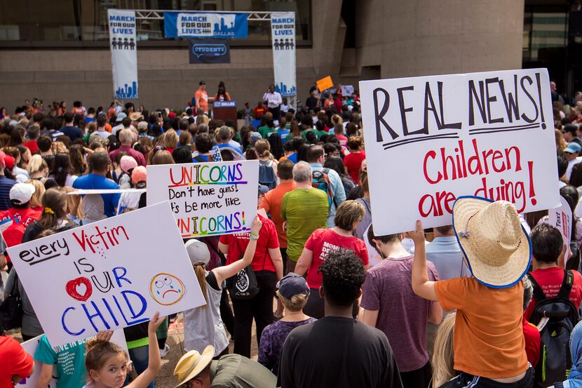 Brooks Herr, 4, holds a sign reading "Real News! Children are dying!" as he listens to...