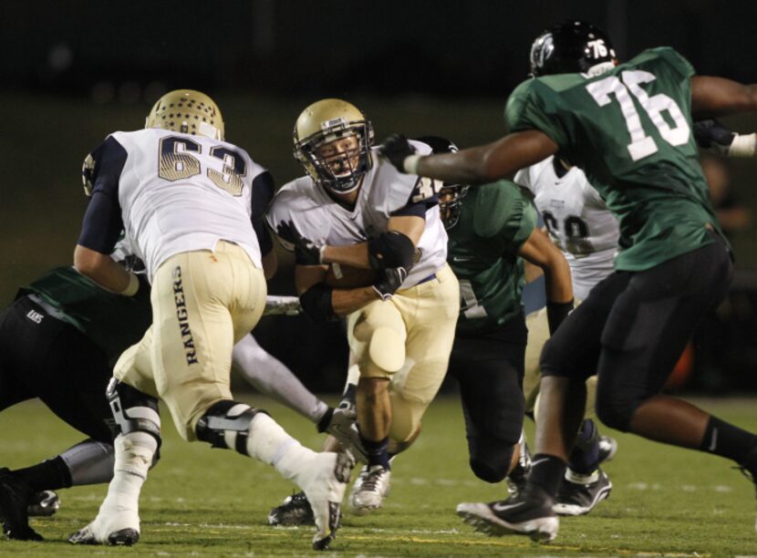 Jesuit running back Adam Holtz, center, carries the ball as offensive lineman Jack Summers...