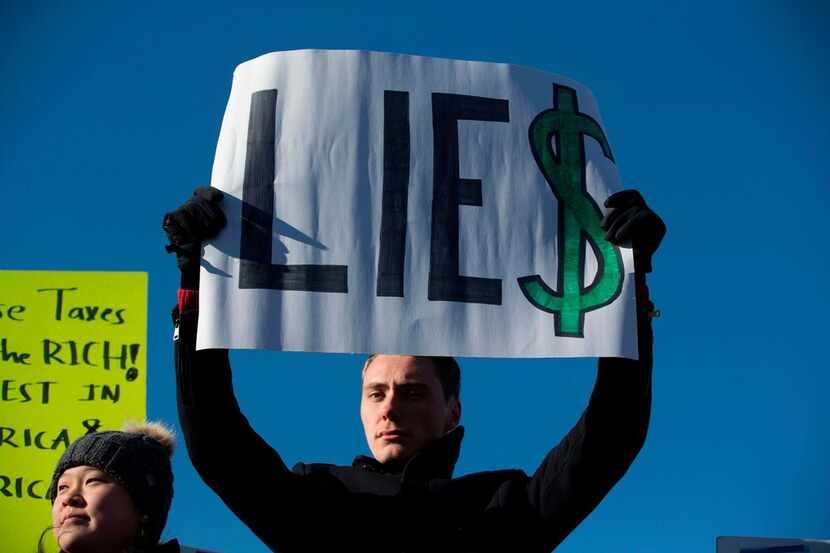 A demonstrator holds a protest sign during a demonstration against Republican-led tax reform...