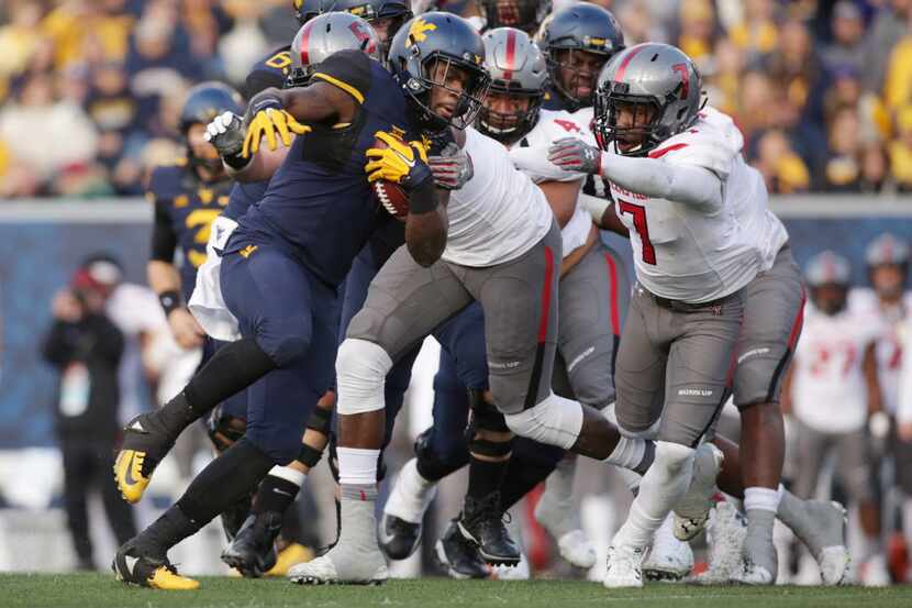 West Virginia running back Wendell Smallwood (4) is tackled by Texas Tech defensive lineman...