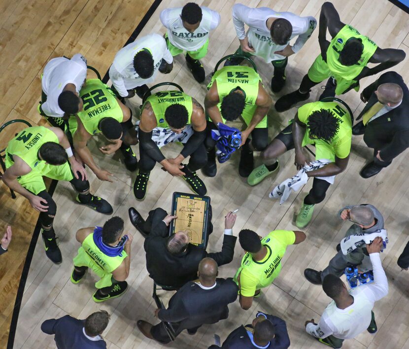 The Baylor team listens intently as head coach Scott Drew draws up a play during a timeout...