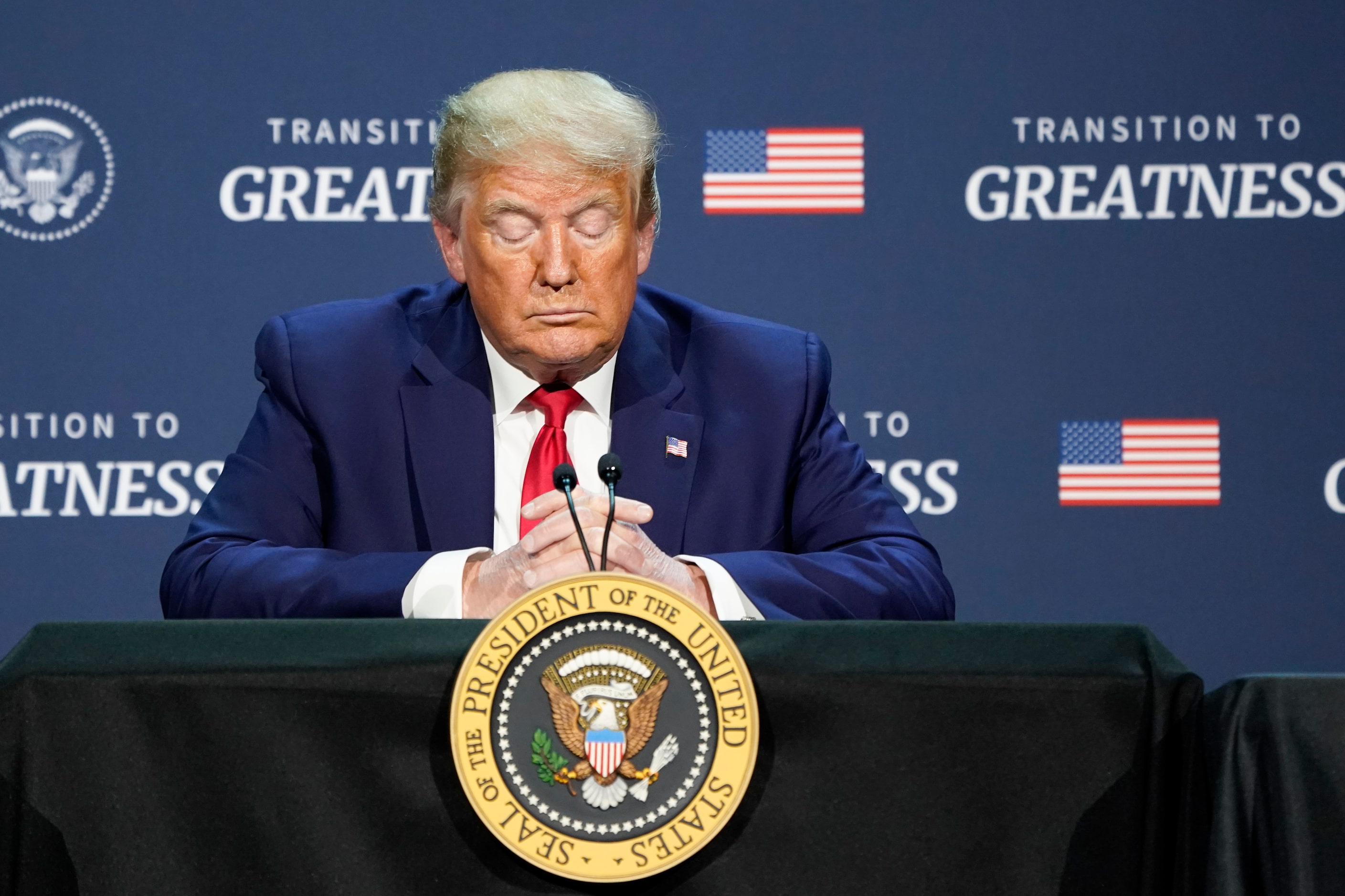 President Donald Trump bows his head in prayer during a roundtable conversation about race...