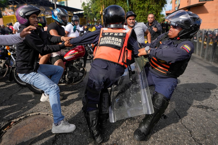 Un manifestante forcejea con la policía en las protestas contra los resultados de las...