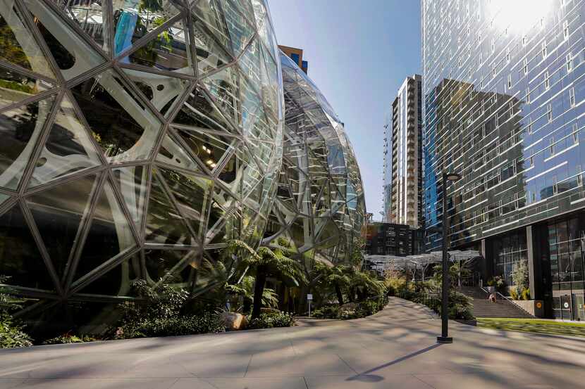 The light reflects off the glass facade of a building on the Amazon campus outside the...