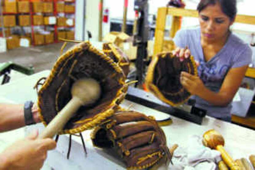  Maria Cedillo shapes a handmade Nokona baseball glove while manager Rob Storey uses a wood...