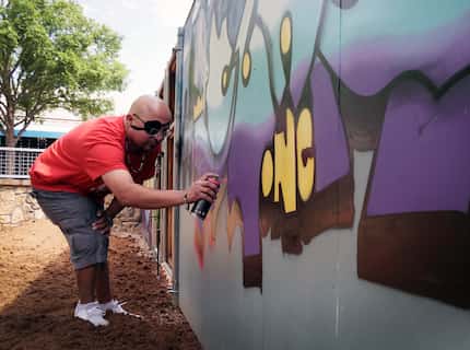 King Suner1 paints a mural on a wall in the Art Park and beer garden at Trinity Groves in...
