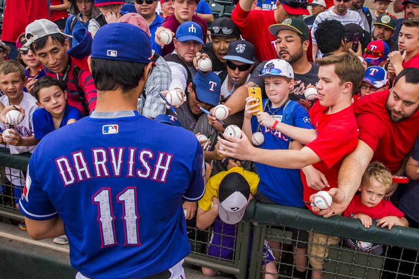 Fans push forward to get an autograph from Texas Rangers pitcher Yu Darvish before a spring...