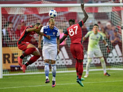 FC Dallas defender Reto Ziegler, center, clears the ball as Toronto FC forward Tosaint...