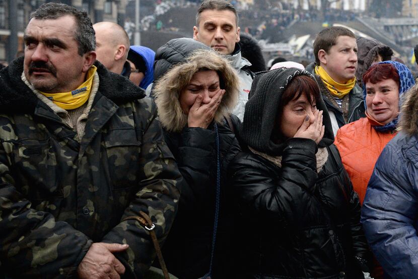 People react as the body of a dead anti-government demonstrator killed in clashes with...