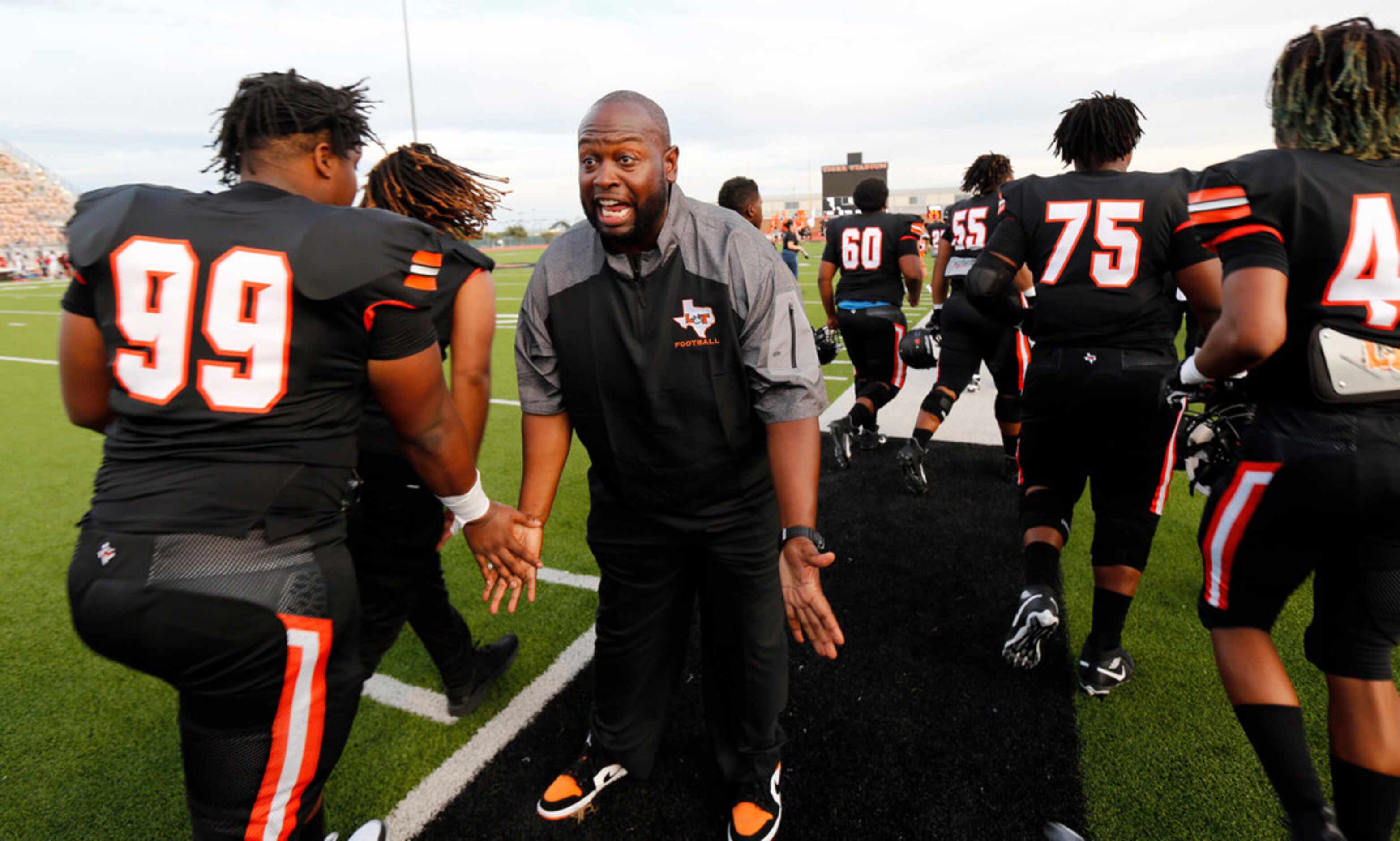Lancaster head coach Christopher Gilbert slpas hands with his players after the team's...