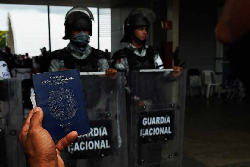 ARCHIVO - Un migrante sostiene su pasaporte venezolano frente al Centro de Atención Integral...
