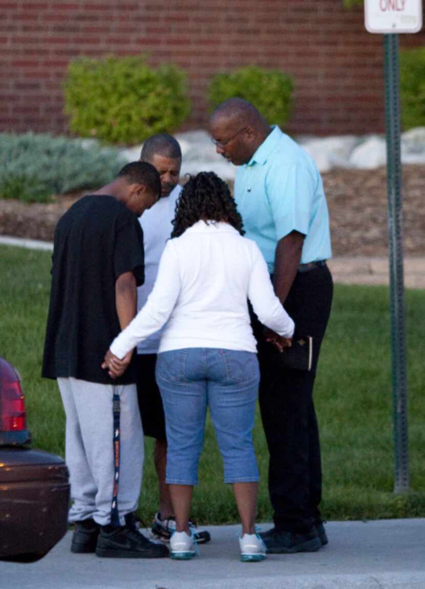 A small group prays outside Gateway High School where witness were brought for questioning...